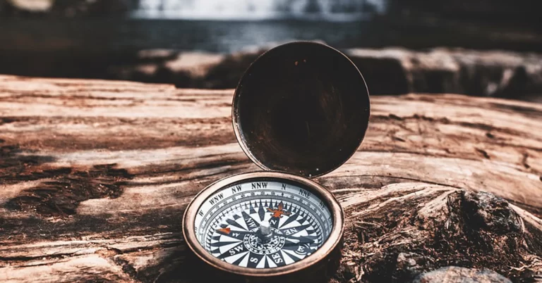 Compass On Log With Waterfall In Background